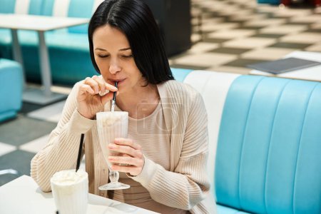 Eine Frau genießt in einem Restaurant einen cremigen Milchshake und genießt den Moment mit einem Lächeln im Gesicht.