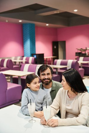 Téléchargez les photos : A happy family sitting at a restaurant table, enjoying a time together in a modern setting during the weekend. - en image libre de droit