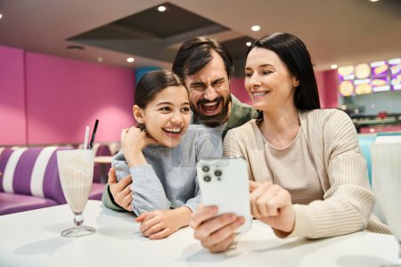 A joyful family gathers at a restaurant, happily taking a selfie together to preserve their weekend memories.