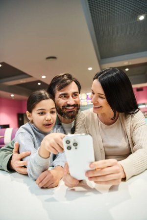 A happy family is smiling and posing for a photo with their cell phone during a weekend outing.