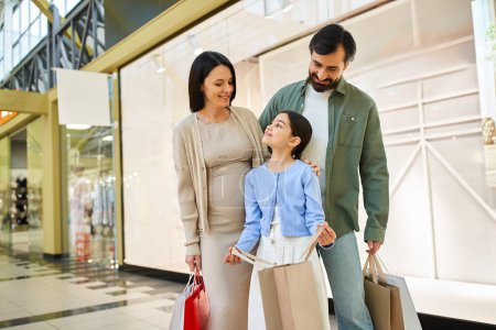 Eine glückliche vierköpfige Familie hält mehrere bunte Einkaufstüten in der Hand, während sie auf einem Wochenendausflug durch ein belebtes Einkaufszentrum läuft..