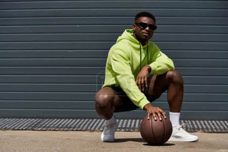 Young man in green hoodie crouching with basketball in hand.