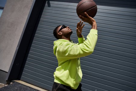 Schöner Mann in grünem Kapuzenpulli fängt Basketball.