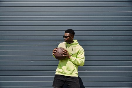 Young man in green hoodie holding basketball.