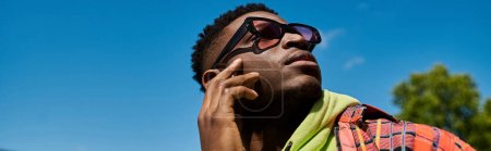 Foto de Hombre afroamericano guapo en gafas de sol posando activamente. - Imagen libre de derechos