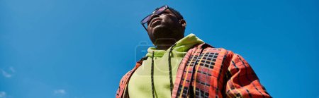 Schöner afroamerikanischer Mann in schicker Kleidung, der in den Himmel starrt.