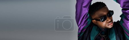 Photo for Stylish young African American man wearing sunglasses and a purple jacket. - Royalty Free Image