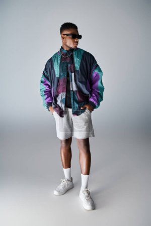 Stylish African American man in colorful jacket and shorts posing confidently.