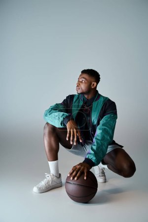Photo for A fashionable African American man crouches with a basketball ball. - Royalty Free Image
