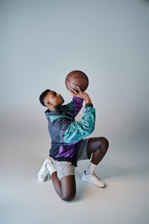 Un elegante jugador de baloncesto afroamericano se agacha para atrapar una pelota.