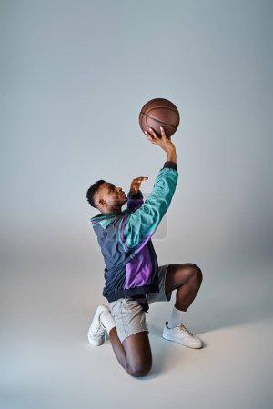 Un elegante jugador de baloncesto afroamericano se agacha para atrapar la pelota.