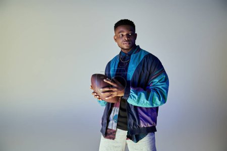Photo for African American man in fashionable attire holding a football. - Royalty Free Image