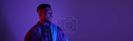 Photo for Handsome African-American man standing confidently against a vibrant purple backdrop. - Royalty Free Image