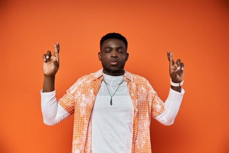 Handsome African American man in stylish orange shirt gestures passionately.