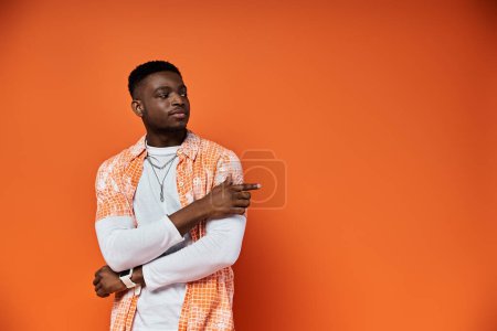 Photo for Stylish African American man in orange shirt posing against matching background. - Royalty Free Image