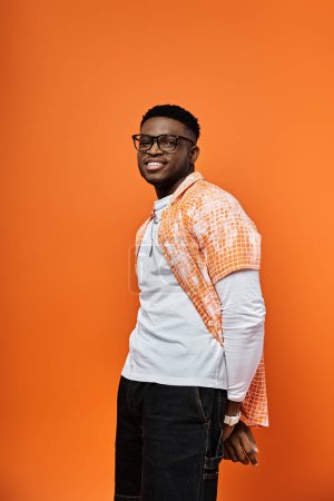 African American man in trendy orange shirt striking a pose against a matching background.