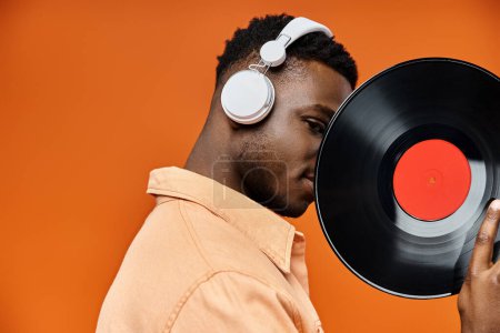 Stylish African American man with headphones holding vinyl record.