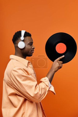 Hombre guapo con auriculares apuntando al disco de vinilo.