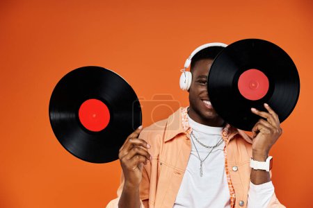 Handsome black man holding two vinyl records in front of him.