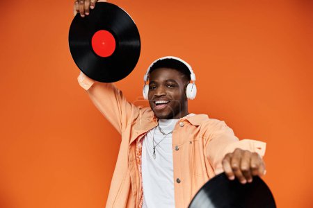 Photo for Young black man in stylish attire holding up a vinyl record. - Royalty Free Image