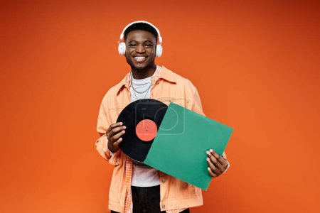 A fashionable young African American man holds a vinyl record.