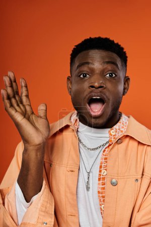 Jeune Afro-Américain en chemise orange, bouche ouverte.