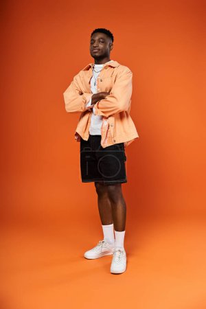 Fashionable man in orange attire against matching background.