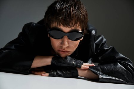 Téléchargez les photos : Young woman in leather jacket and sunglasses laying on a table. - en image libre de droit