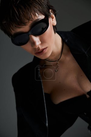 Foto de A beautiful young woman poses confidently in black sunglasses for a fashion shoot. - Imagen libre de derechos