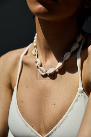 A young woman gracefully wearing a seashell necklace.