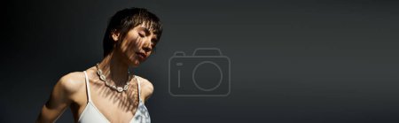 Téléchargez les photos : Elegant woman in white top striking a pose on black background. - en image libre de droit