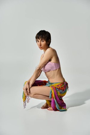 Young woman in colorful bikini crouching on the floor.