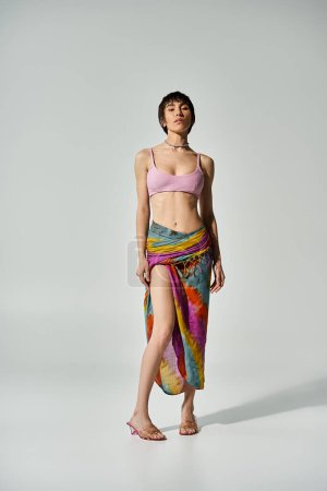 A vibrant young woman in a bikini striking a pose in a colorful skirt.