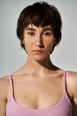 Téléchargez les photos : A young woman with short hair wearing a pink top strikes a stylish pose. - en image libre de droit