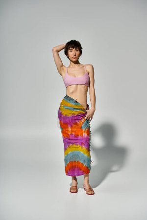 Stylish young woman posing elegantly in a colorful tie dye skirt.