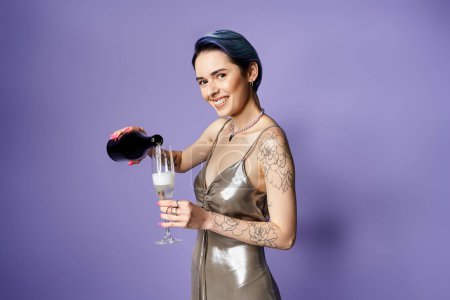 Foto de Young woman with short blue hair looking elegant in a silver dress, holding a glass of champagne at a party. - Imagen libre de derechos