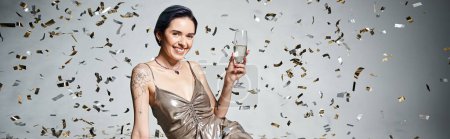 Téléchargez les photos : A young woman with short blue hair elegantly holds a glass of champagne in a silver party dress. - en image libre de droit