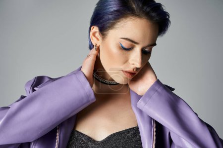 Photo for A stylish young woman with blue hair striking a pose in a purple jacket in a studio setting. - Royalty Free Image