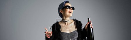 Téléchargez les photos : A stylish young woman with short dyed hair striking a pose in a black dress while holding champagne - en image libre de droit