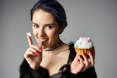 Stylish young woman holds a cupcake, exuding an air of sophistication and rebellion.