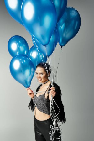 Photo for A stylish young woman with short dyed hair holding a bunch of blue balloons. - Royalty Free Image