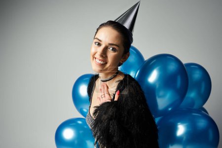 Téléchargez les photos : Young woman with stylish attire and short dyed hair strikes a pose in a party hat for a celebratory occasion. - en image libre de droit