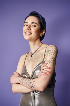 Téléchargez les photos : A young woman with blue hair strikes a pose in a stunning silver dress, showcasing intricate tattoos on her arms. - en image libre de droit