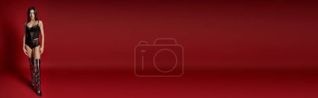 Téléchargez les photos : A woman in a black lingerie and wet hair standing confidently against a vibrant red background. - en image libre de droit