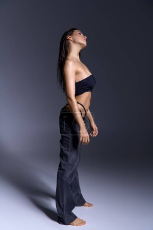 Foto de Young woman in stylish black bikini top and pants with wet hair. - Imagen libre de derechos