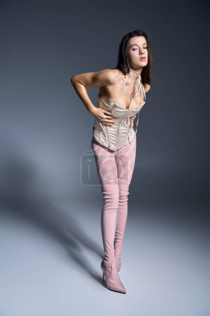 Young woman in pink tights and boots striking a stylish pose.