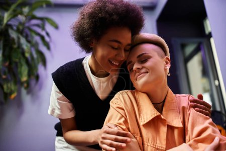 A diverse couple of lesbians hugging lovingly in a cozy cafe.