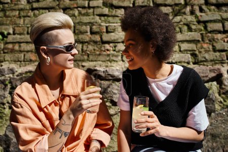 Téléchargez les photos : Deux femmes belles et diversifiées sont assises à proximité, absorbées par la conversation dans un café. - en image libre de droit