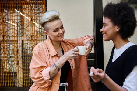 Zwei unterschiedliche Frauen stehen dicht beieinander und teilen sich einen Moment in einem Café.