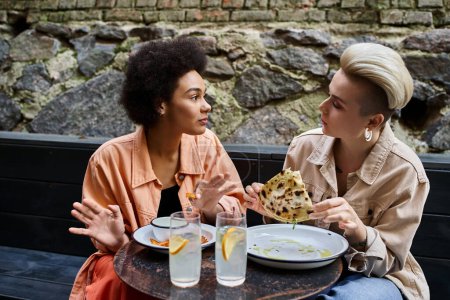 Téléchargez les photos : Deux femmes dégustant un repas ensemble à une table dans un restaurant. - en image libre de droit